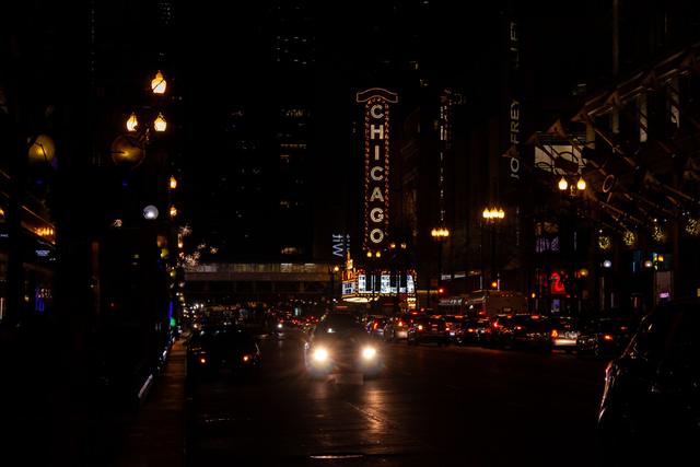 A downtown Chicago street at night, with traffic lights and illuminated towers